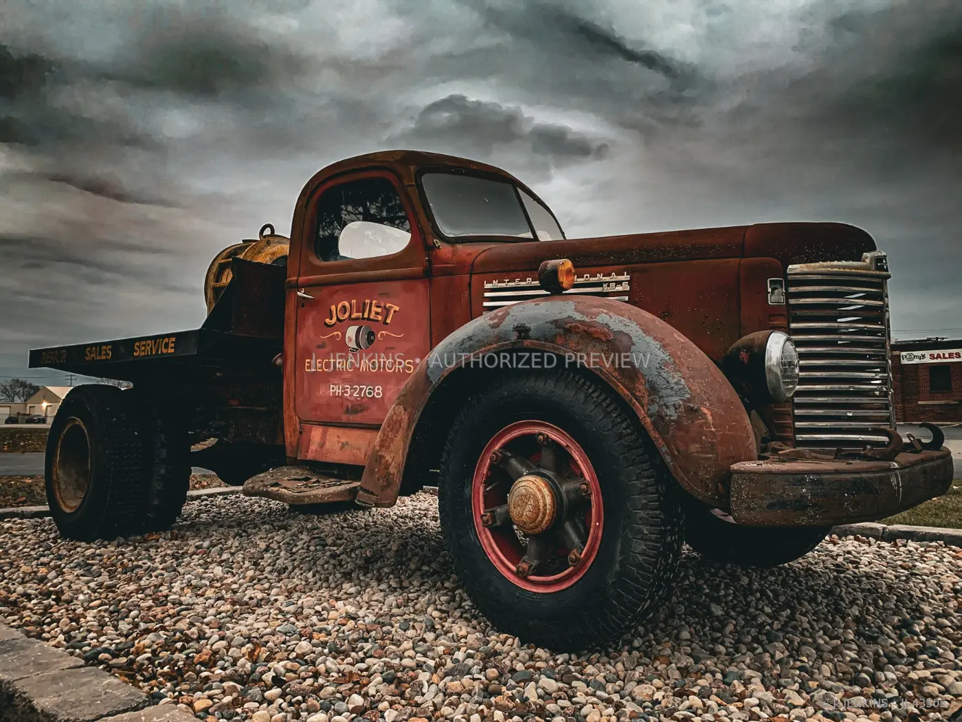 Rust-red vintage service truck under heavy clouds