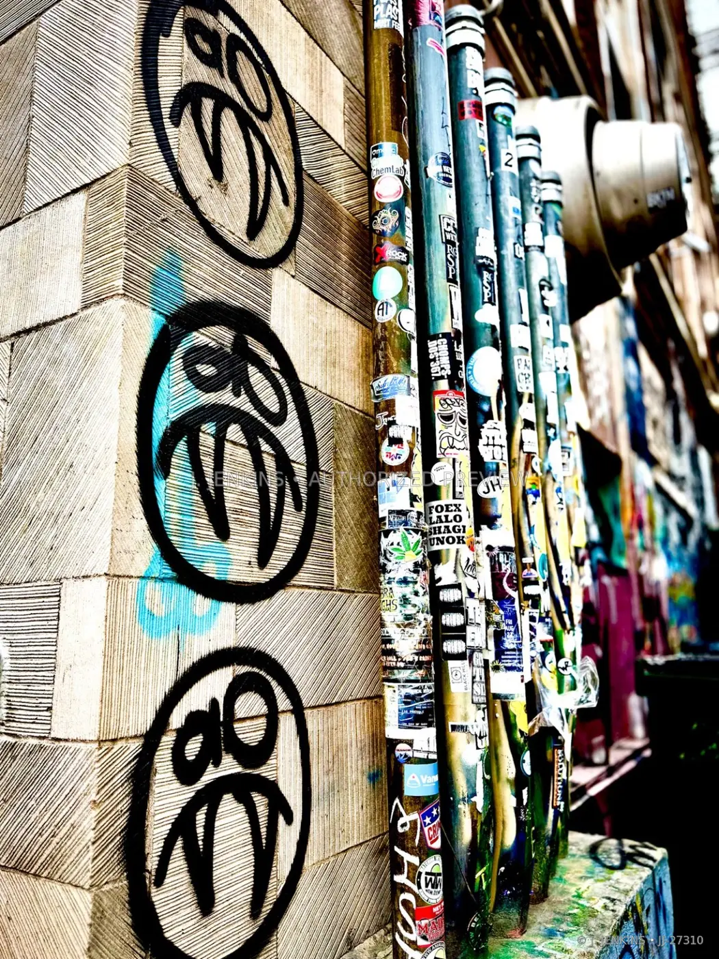 Sticker-covered utility pipes beside black wall marks