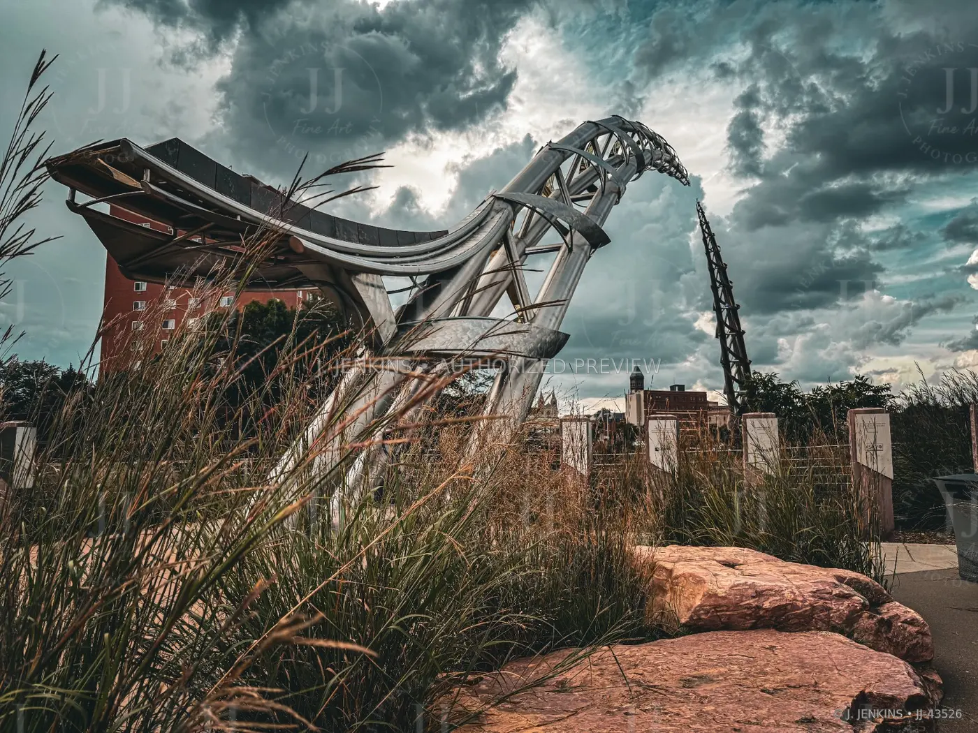 Steel sculpture rising above grasses under a stormy sky