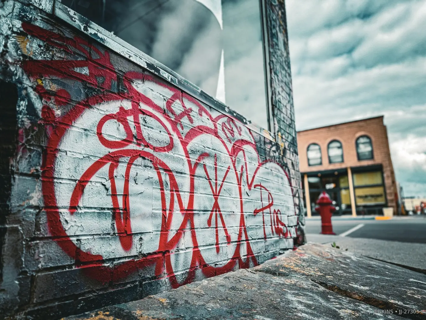 Red graffiti crossing a weathered white brick wall